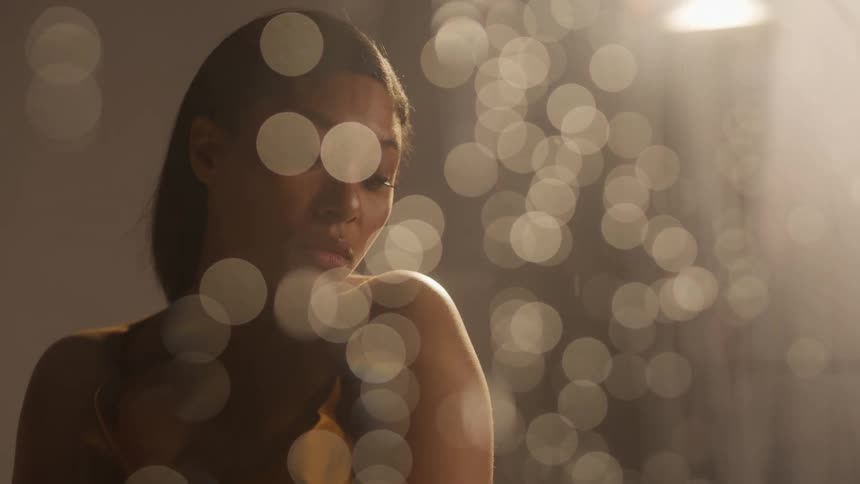 Woman poses on other side of glass as raindrops flow down glass surface