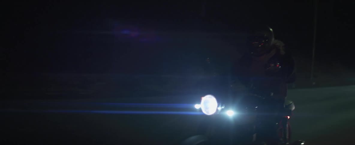 A person riding a motorcycle at a high speed in a highway during the night