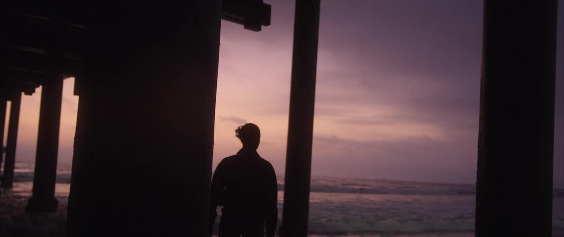 Woman silhouetted against the sky walk on beach near pier