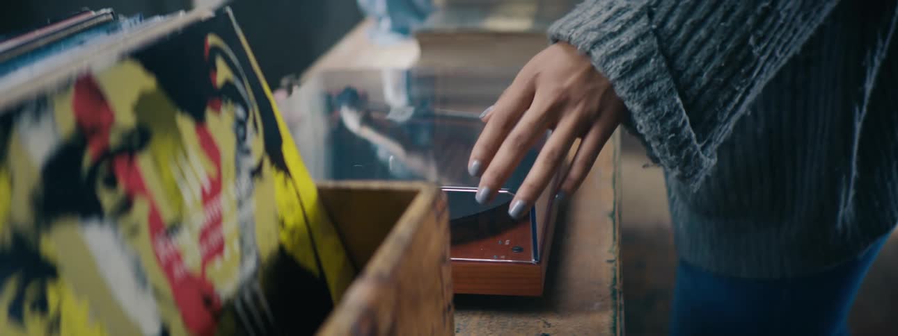 Woman throws an old record on to play in a cozy living room setting with a friend