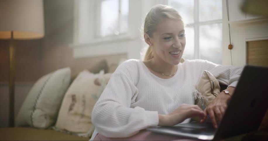 Young woman works virtually from home and interacts with someone through her screen