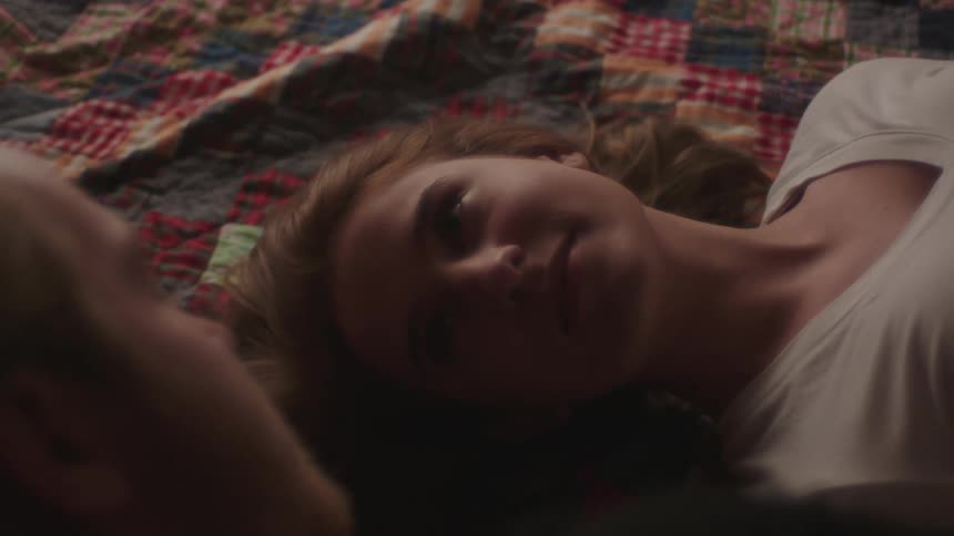 A woman listens to a man lying beside her on a blanket as he speaks