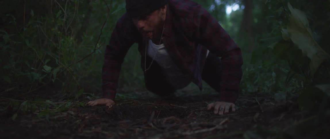 Man comes too with face in water and stands and staggers along trail through woods