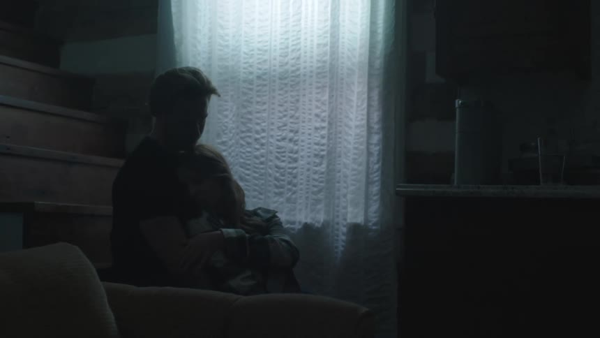 Couple hugging each other sitting on the stairs of a house with the woman caressing her boyfriends arm