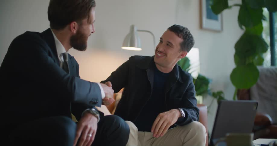 Two men having a business meeting in the living room shake hands