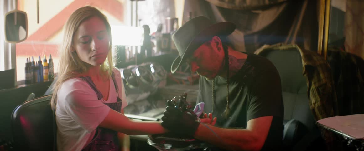 A man tattooing a woman's forearm