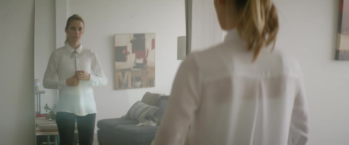 A woman is adjusting her clothes in front of a mirror