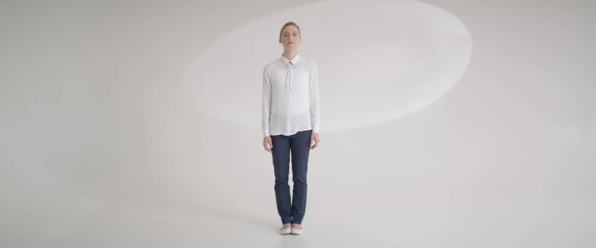 A woman is standing looking up then straight forward