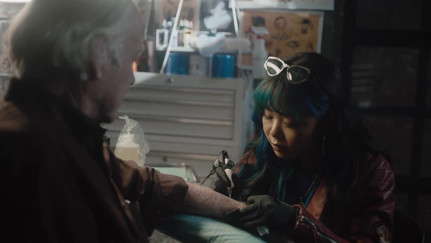 An elderly man is getting a tattoo