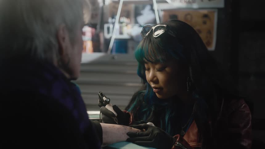 Tattoo artists works on clients arm
