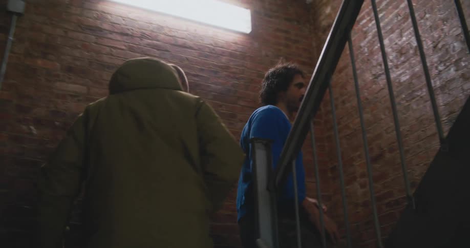 Two men climb the brick stairwell