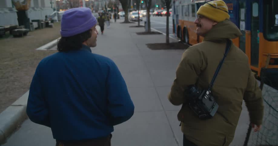 Man signs while walking along busy city street with friend