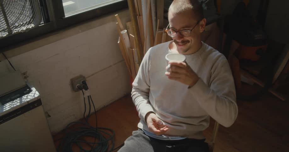A man is talking while he drinks coffee