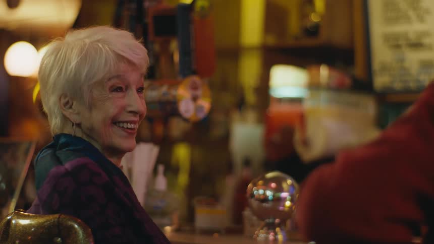 A woman sitting at the bar giggling and flirting with the man beside her