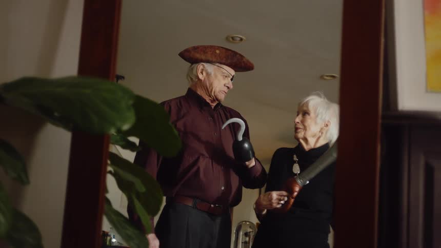 An elderly couple check out their pirate costumes in the mirror