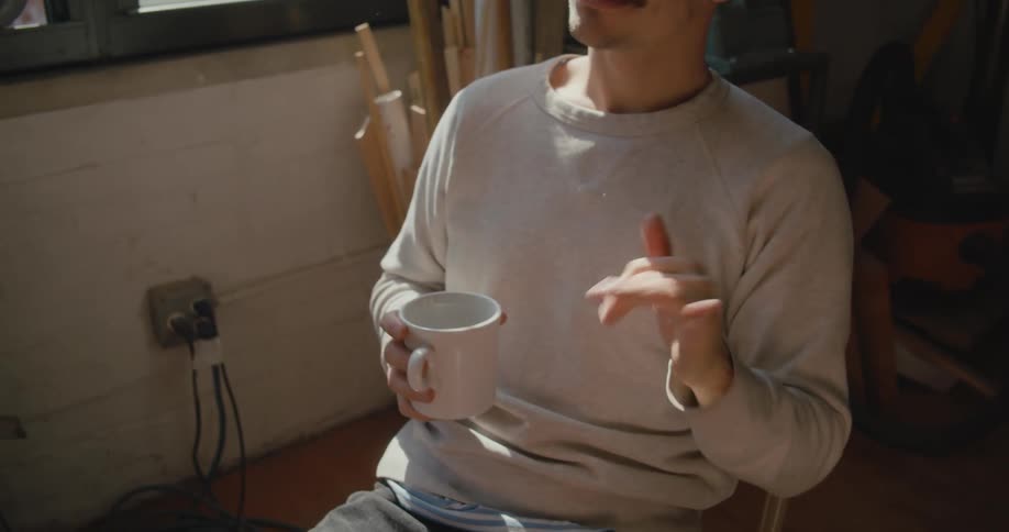 A man is sitting with a cup of coffee and talking