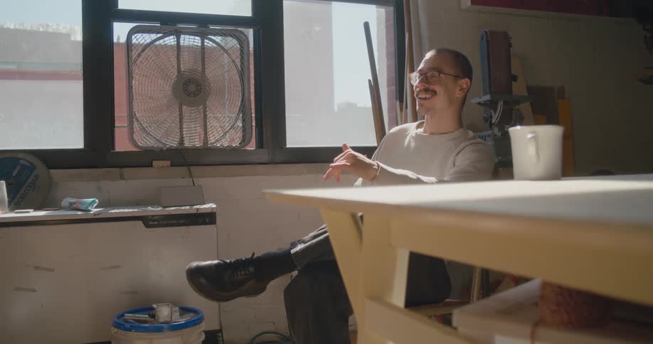 Man sitting near window signs and smiles before picking up coffee cup
