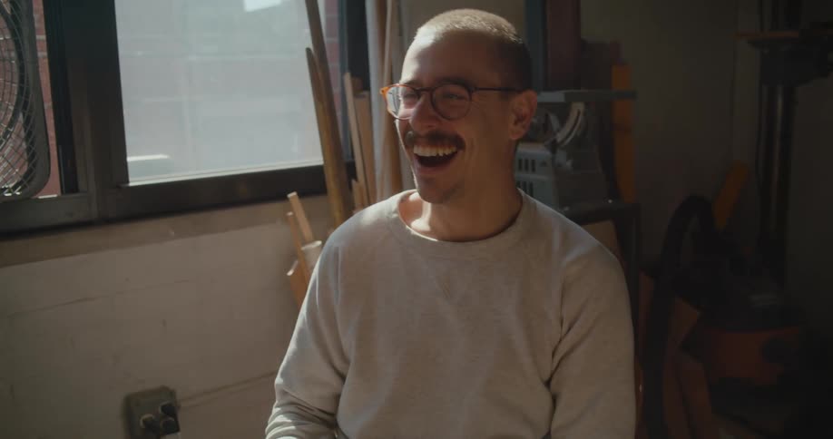 A man is smiling and laughing while talking to someone