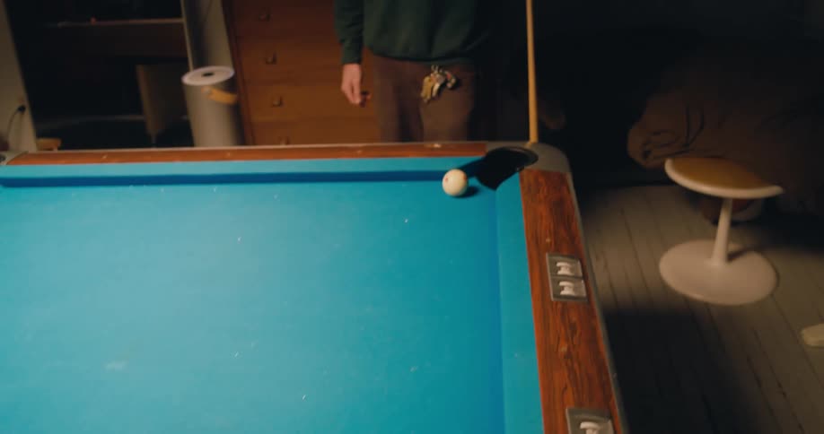 A man uses a pool stick to hit a ball into a hole on a pool table before being congratulated by his opponent