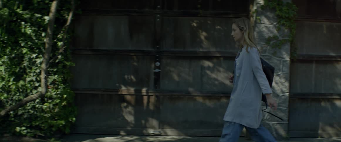 A blond woman walks near a garage