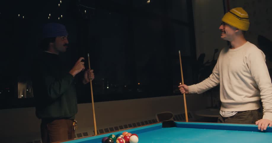 Two men talk as they play pool