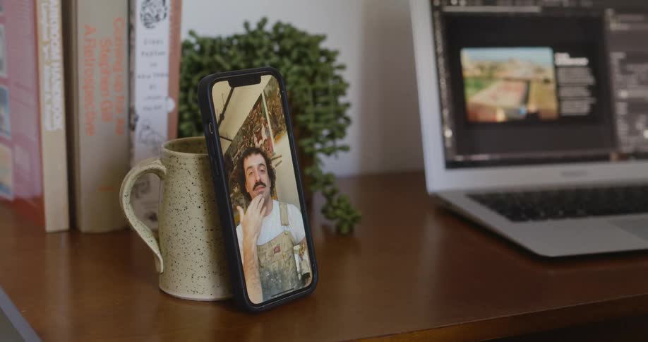 Smartphone propped against cup next to laptop on desk