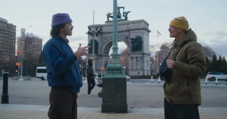Friends stand using sign language near plaza with landmark structure in the background