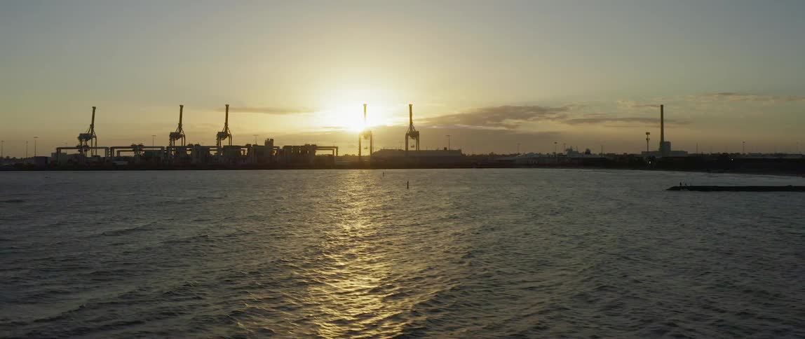 The water is rough around the port at sunset