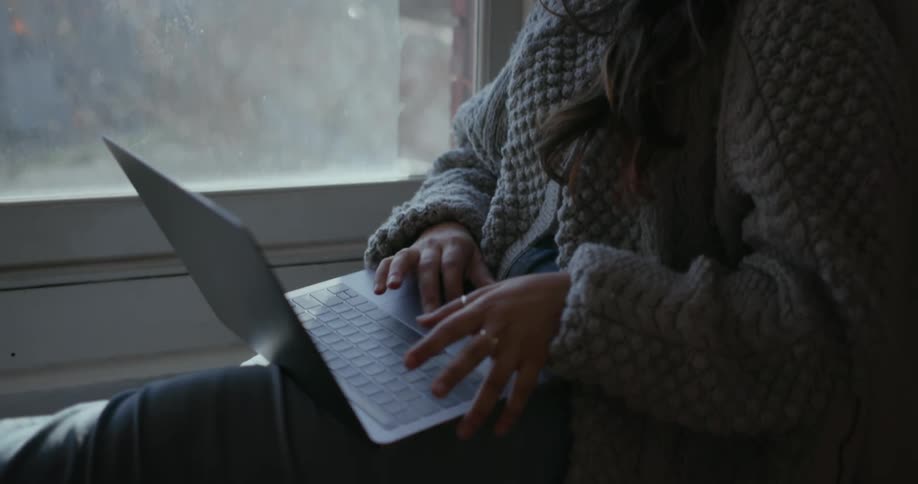 A woman uses her laptop by the window