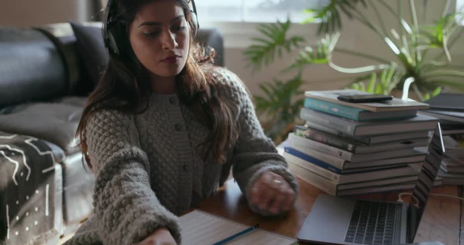 A woman plays a keyboard while wearing headphones