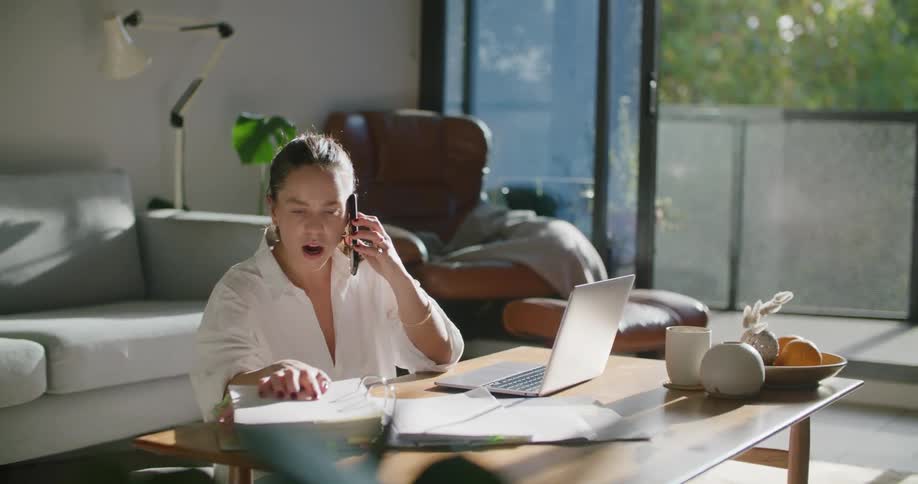 A woman talking on a phone looking through a notebook