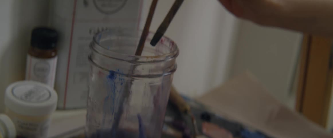 A person cleans their brush as they paint