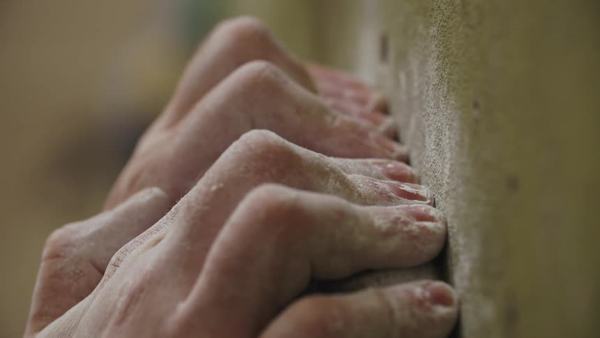 Fingers with white powder on them grasp onto a small ledge that is covered with white powder