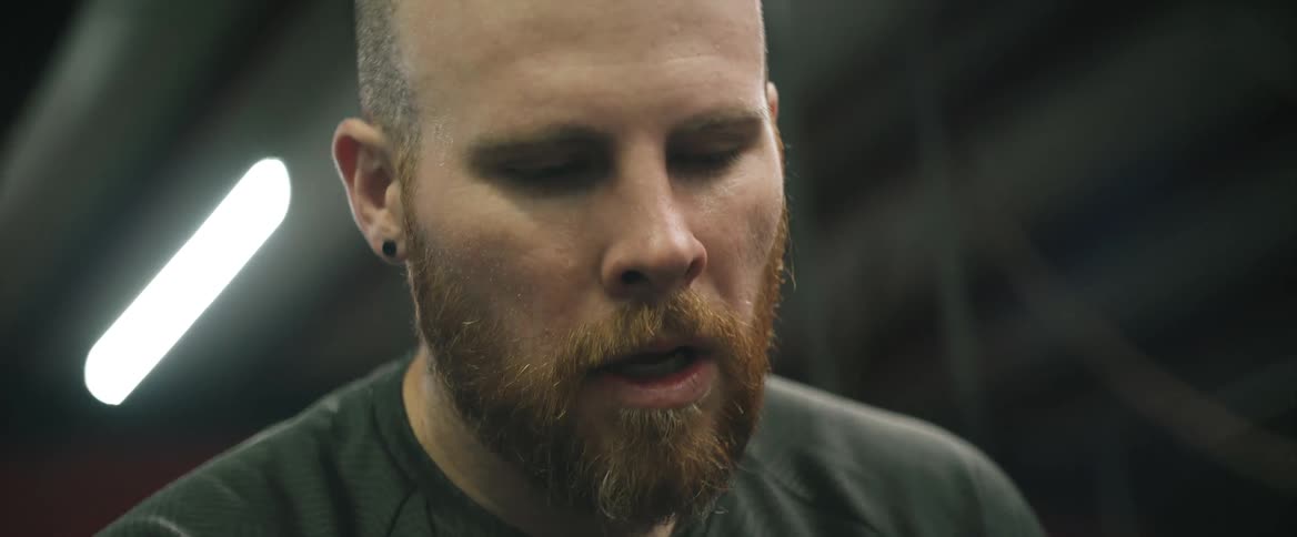 A man exhales deeply after wiping the sweat off his forehead during excercise