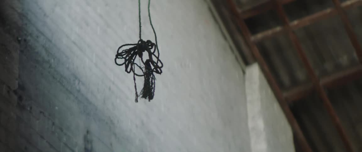 Black string of cord hanging from the ceiling of a warehouse