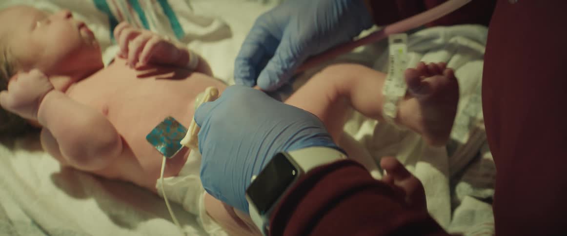 Doctor wearing blue latex gloves uses a stethoscope on a baby in the hospital