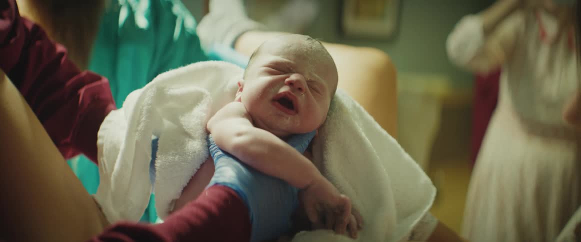 A newborn is lifted up in a towel