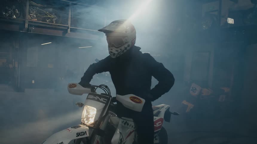 A person is sitting on a motorcycle inside of a garage