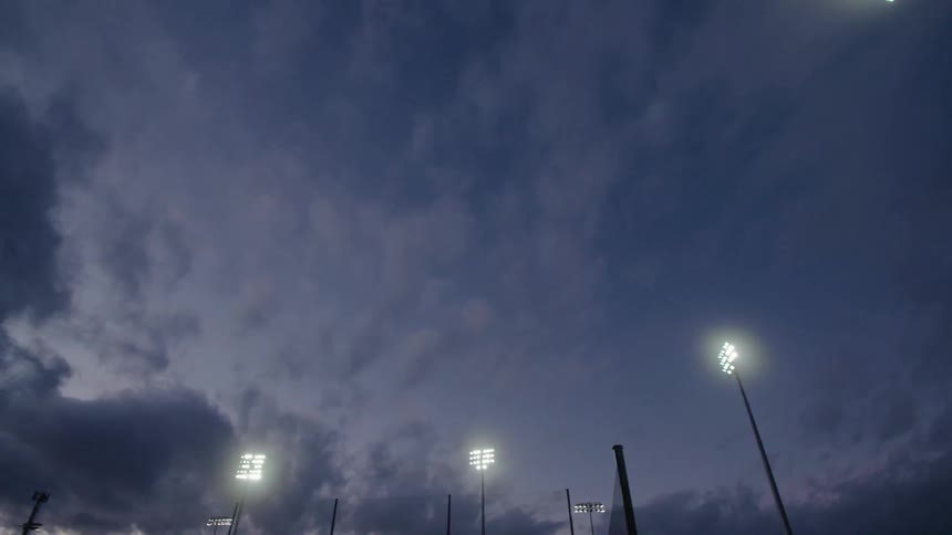 Several tall poles have bright flood lights situated on them to illuminate the area below