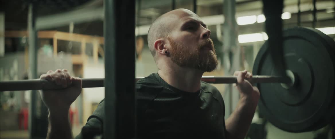 A man does squats with weights exhaling as he rises