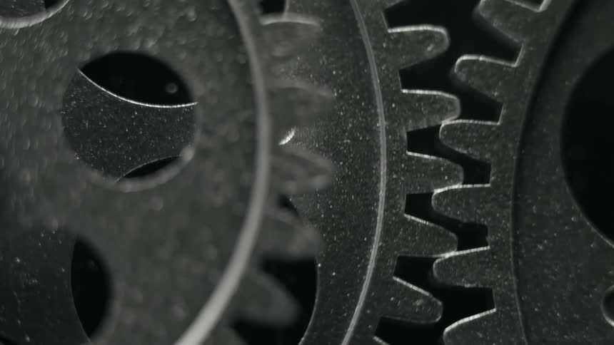 The teeth of turning cogs fit together as they rotate