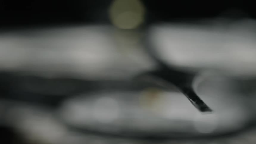 The arm of a dial ticks as a blur of clouds and light rotate