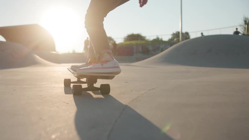 Legs of a girl balancing and doing tricks on a skateboard on a skate park on a sunny day