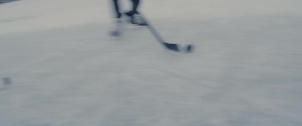 Youths play ice hockey on frozen water near homes as others watch
