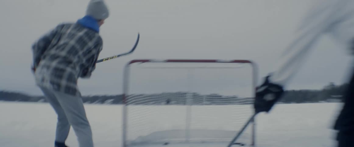 Young man scoring a point and then celebrating it in a friendly ice hockey match outdoors during a snowy day