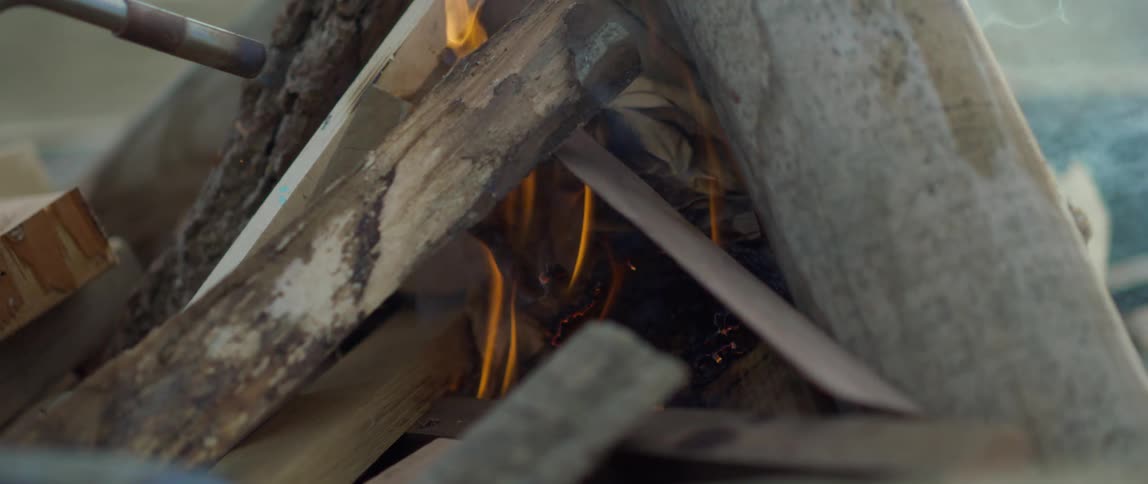 Person lights outdoor fire with a torch