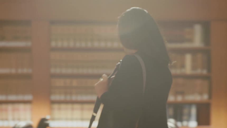 A woman walks into a library and sets her bag down at an open table