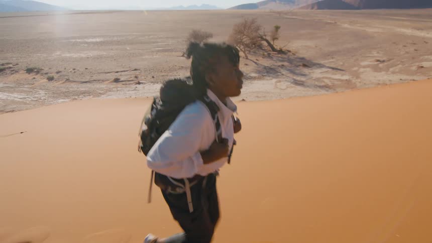 Woman hikes up a desert sand dune