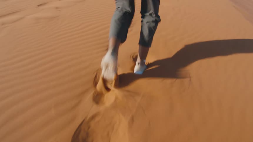 Close up of feet hiking up sand dune in the desert