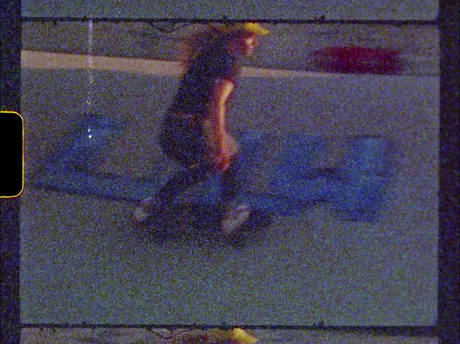 Woman with long hair and wearing a cap skateboards on the ramps in a skateboard park on a sunny day